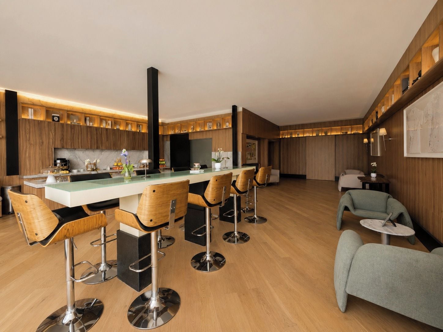 Une cuisine moderne dotée d’un îlot central, de tabourets de bar et de meubles de rangement en bois.