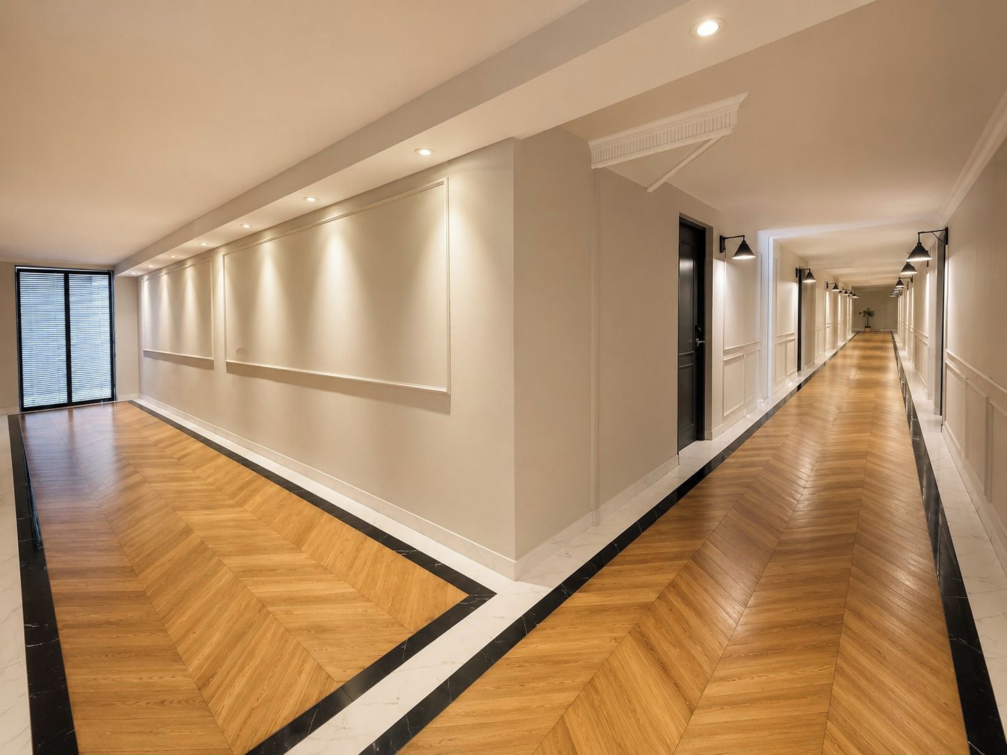 A long, narrow hallway with wooden flooring and white walls, featuring recessed lighting and a door at the end.