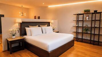 Una habitación de hotel moderna con una cama grande, lámparas de noche, suelo de madera y una estantería empotrada.