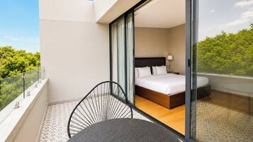 Habitación de hotel con balcón, cama, silla y mesa.