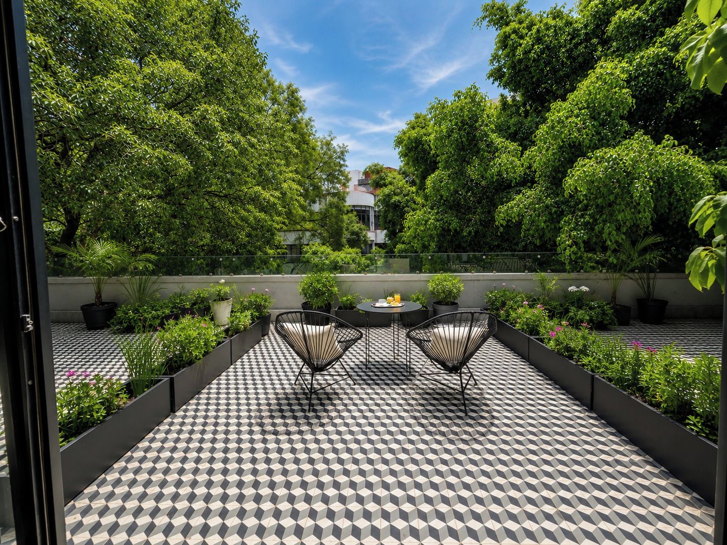 A rooftop terrace with a checkered floor, two black chairs, and a table with a drink.