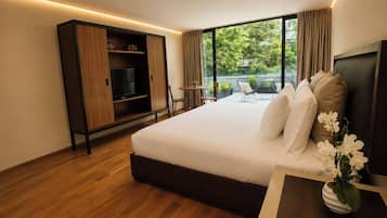 A modern hotel room with a large bed, a TV, a wardrobe, and a balcony with outdoor seating.