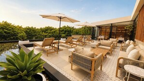 Una terraza en la azotea con sillones de descanso, una piscina pequeña y un área de comedor.