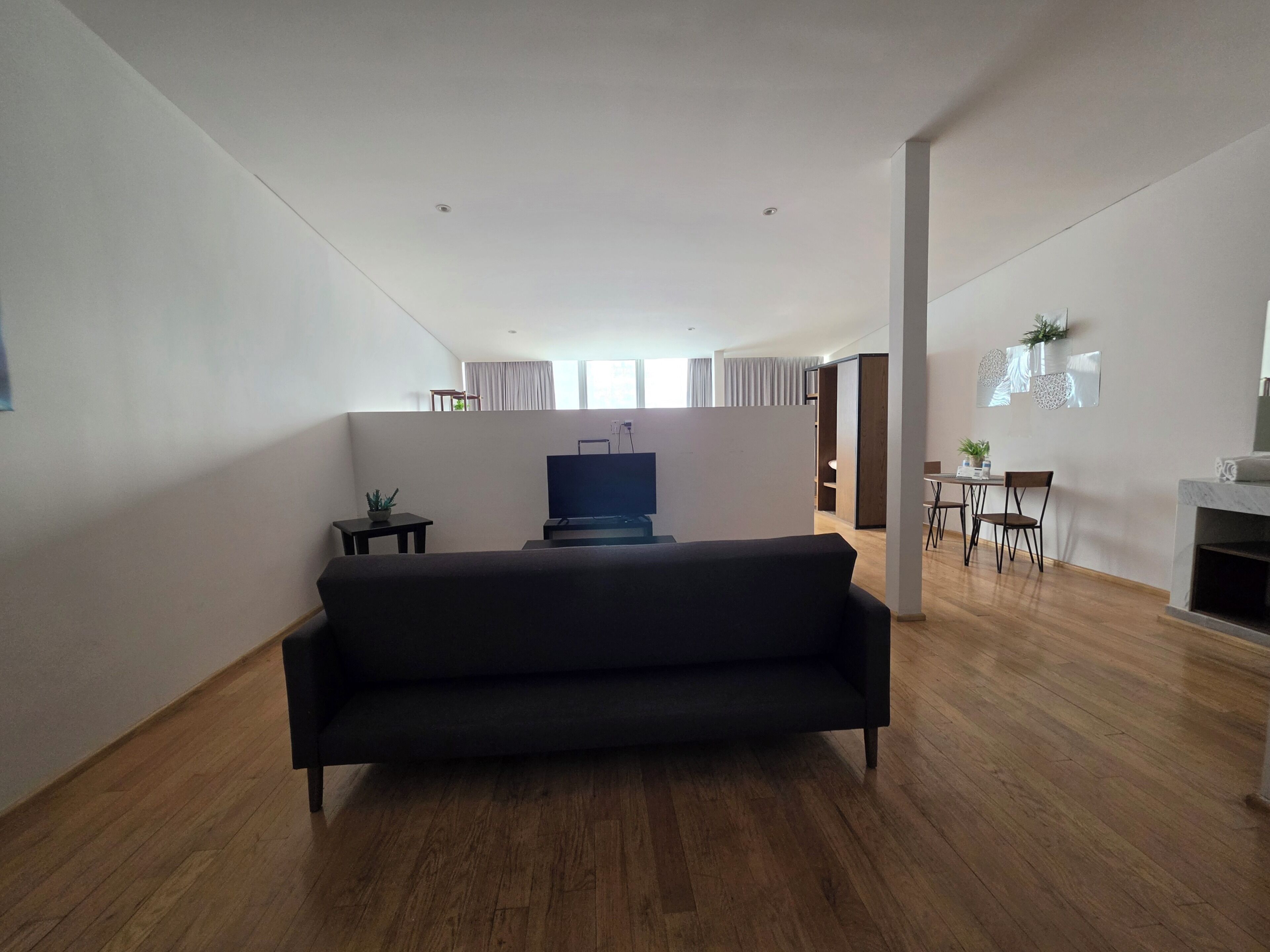 Una sala de estar moderna con un sofá, una televisión y un comedor con sillas y una mesa.