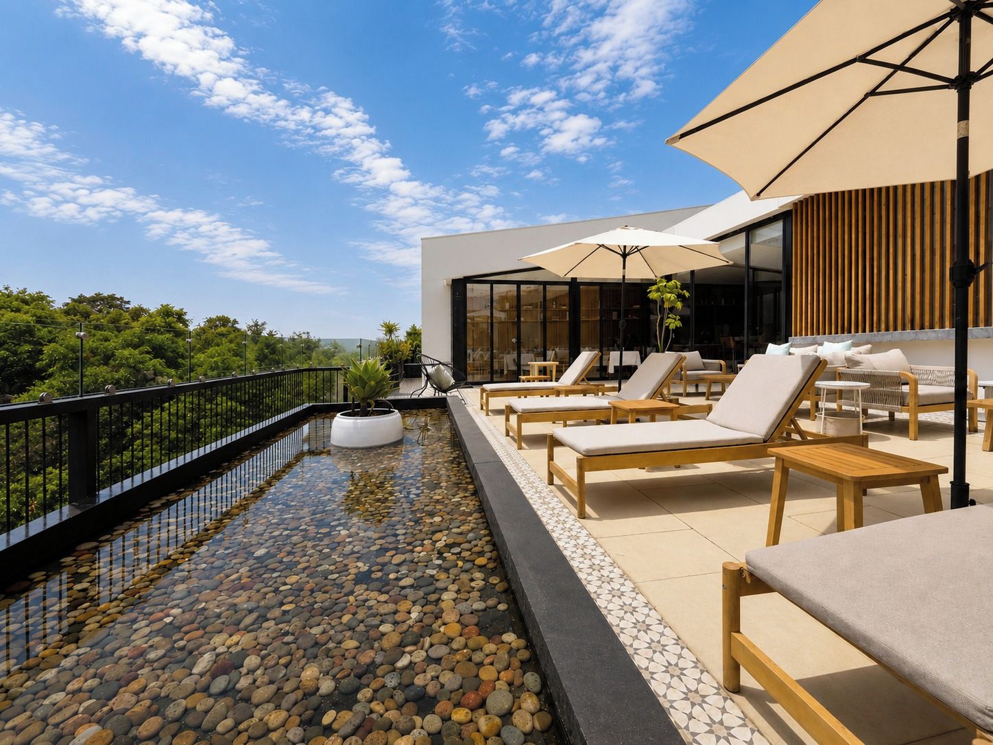 A rooftop terrace with a pool, lounge chairs, and umbrellas.