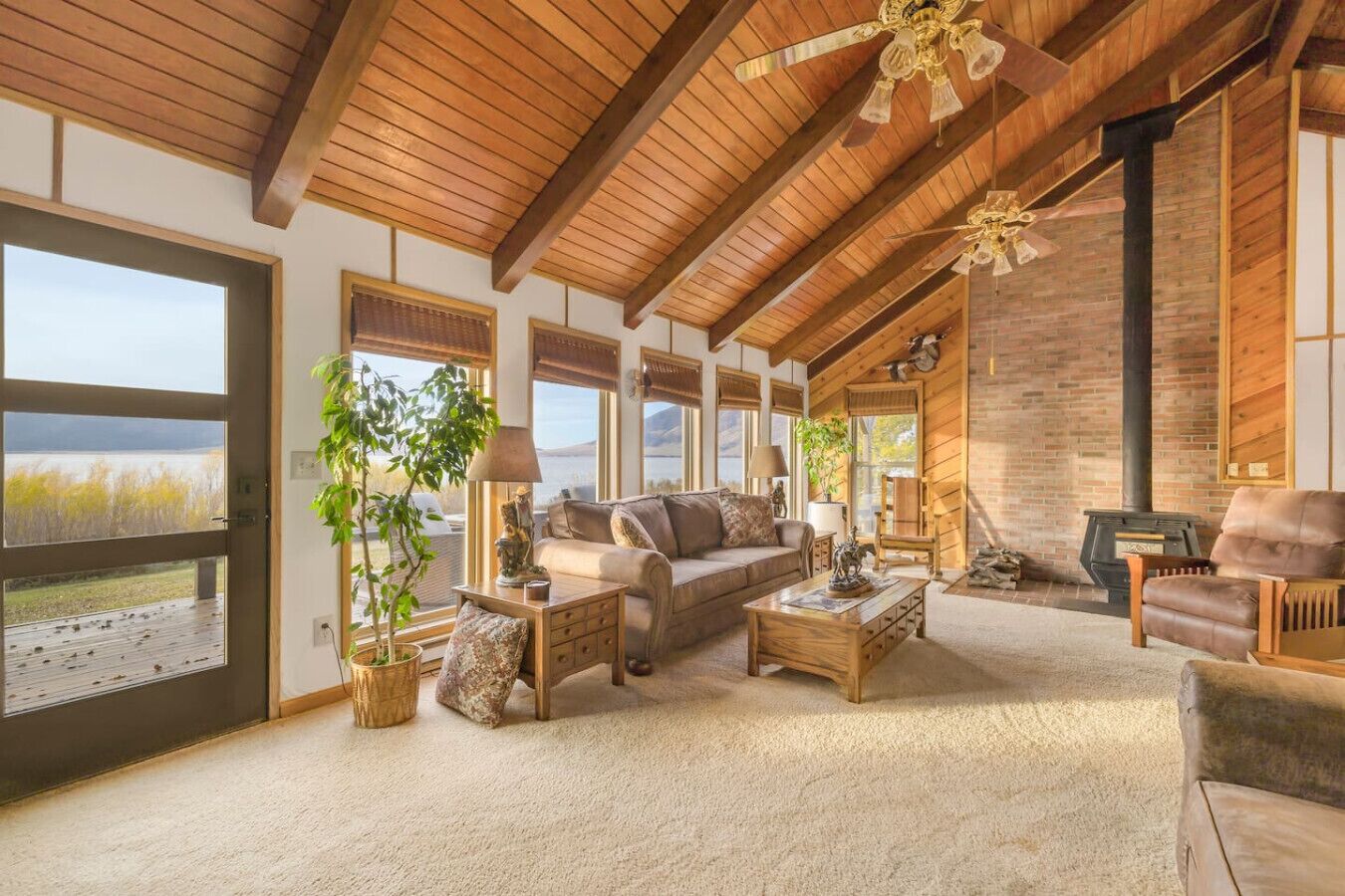 A spacious living room with a large window, a fireplace, and a ceiling fan.