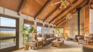 A spacious living room with a large window, a fireplace, and a ceiling fan.