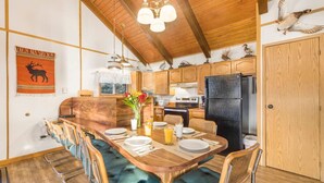 A kitchen with wooden cabinets, a black refrigerator, and a dining area with a wooden table and chairs.