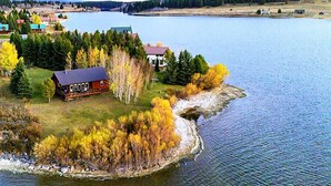 Ein Ferienhaus am See mit Steg, umgeben von Herbstlaub und einem bewaldeten Gebiet.