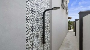 A narrow outdoor corridor with a tiled wall on one side and a concrete pathway on the other. - Beachfront Condo | Pool + Hot Tub | Near Seawall (Galveston)