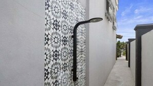 Un étroit couloir extérieur avec un mur orné de motifs et une structure en métal noir.