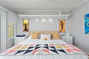 Una camera da letto con un letto grande, comodini bianchi e opere d'arte alle pareti.