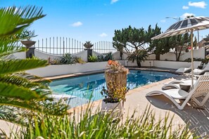 Relax by the pool surrounded by lush greenery and comfortable lounge seating.