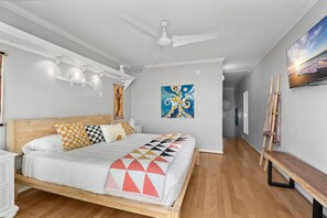 Cozy retreat with a comfortable bed, ceiling fan, and artwork on the wall.