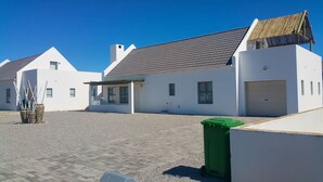 Ein modernes Gebäude mit einem Ziegeldach, einer überdachten Terrasse und einer grünen Mülltonne.