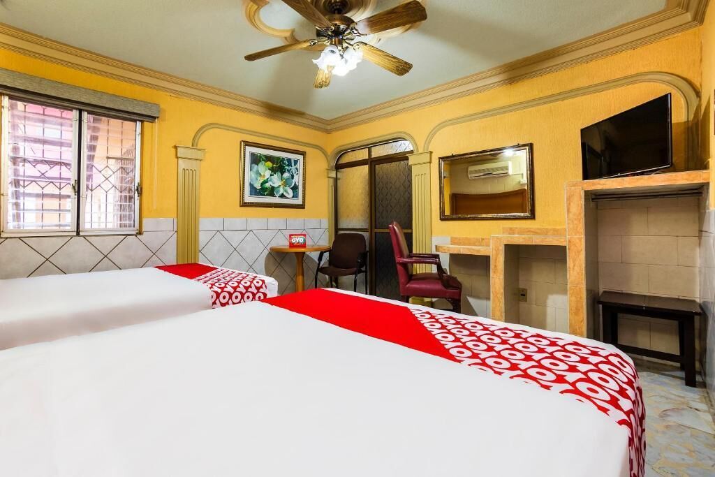 Camera d'albergo con due letti, una ventola a soffitto, una TV, un camino e un piccolo tavolo con una sedia.