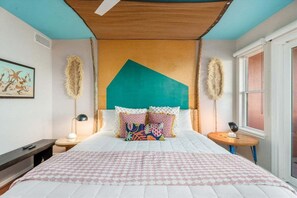 Un dormitorio con cama, mesita de noche, una mesa redonda y ventana.