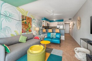 Un espace de vie compact comprenant un coin cuisine, un canapé, une chaise et une petite table.