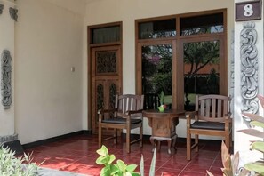 A room with a tiled floor, two wooden chairs, a small table, and a large window with a view of greenery. - Banyualit Spa 'n Resort Lovina (Bali)
