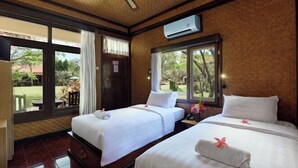 A hotel room with two beds, a window with a view of the garden, and an air conditioning unit on the wall. - Banyualit Spa 'n Resort Lovina (Bali)