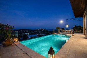 Une piscine rectangulaire offrant une vue sur le paysage urbain illuminé la nuit.