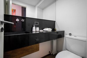 A modern bathroom with a black countertop, white fixtures, and a visible toilet. - MOT Honduras 5740 (Buenos Aires)