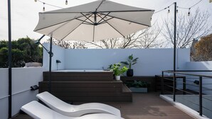 Une terrasse sur le toit dotée d’un grand parasol, d’une plateforme en bois et d’un espace salon.