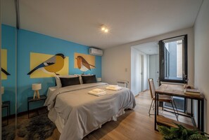 A bedroom with a bed, a desk, a chair, a radiator, and a window. - MOT Honduras 5740 (Buenos Aires)