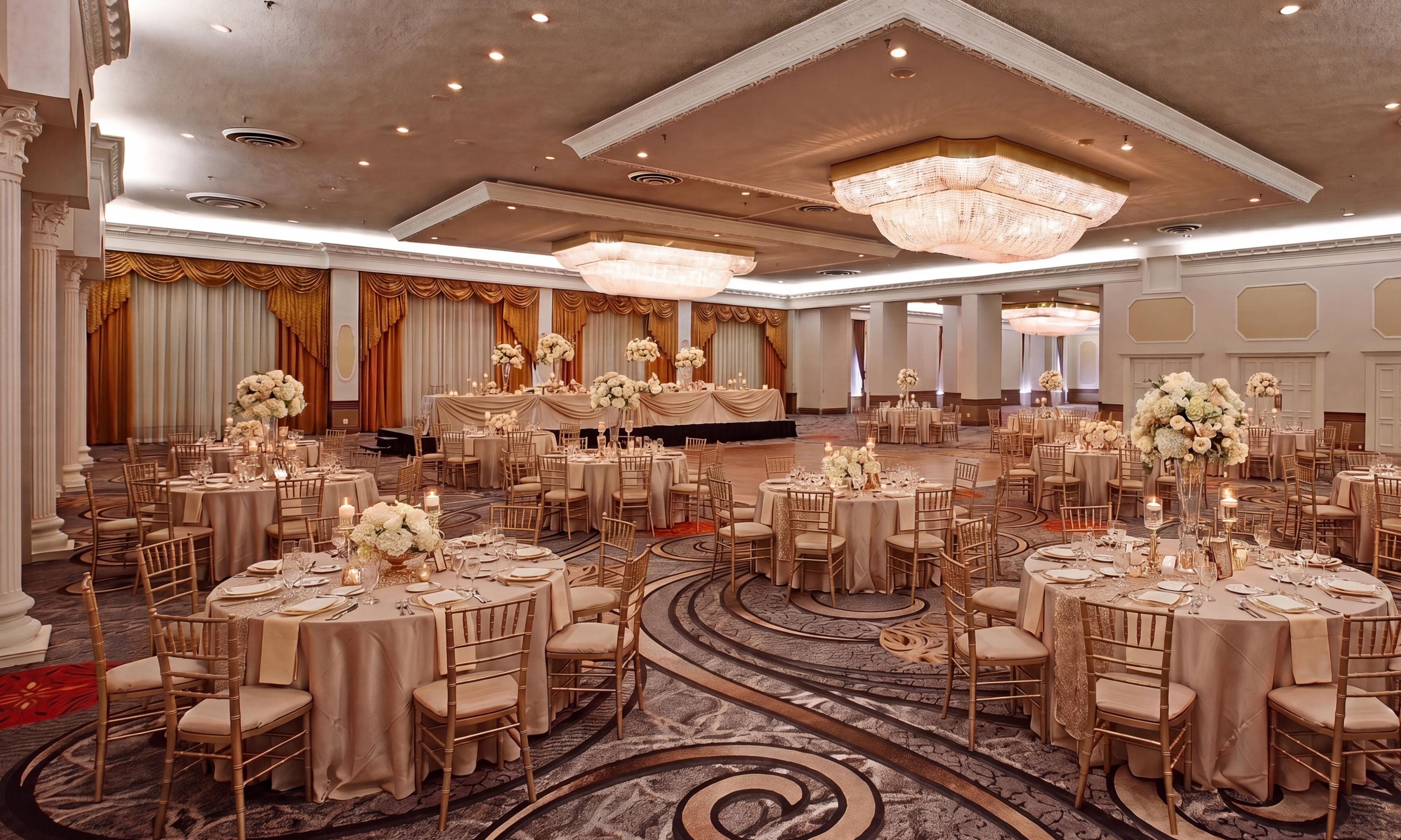 A banquet hall with round tables, chairs, and a stage.
