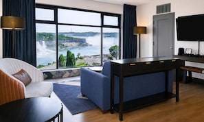 Hotellihuone, jossa on suuri ikkuna, josta avautuu näkymä vesiputoukselle ja vehreään maisemaan.