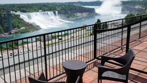 A balcony with wicker furniture overlooking a river with waterfalls. - The Brock Niagara Falls Fallsview, Tapestry by Hilton (Niagara Falls)
