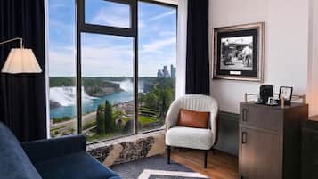 Habitación de hotel moderna con un ventanal que ofrece vistas a una cascada y al paisaje urbano.