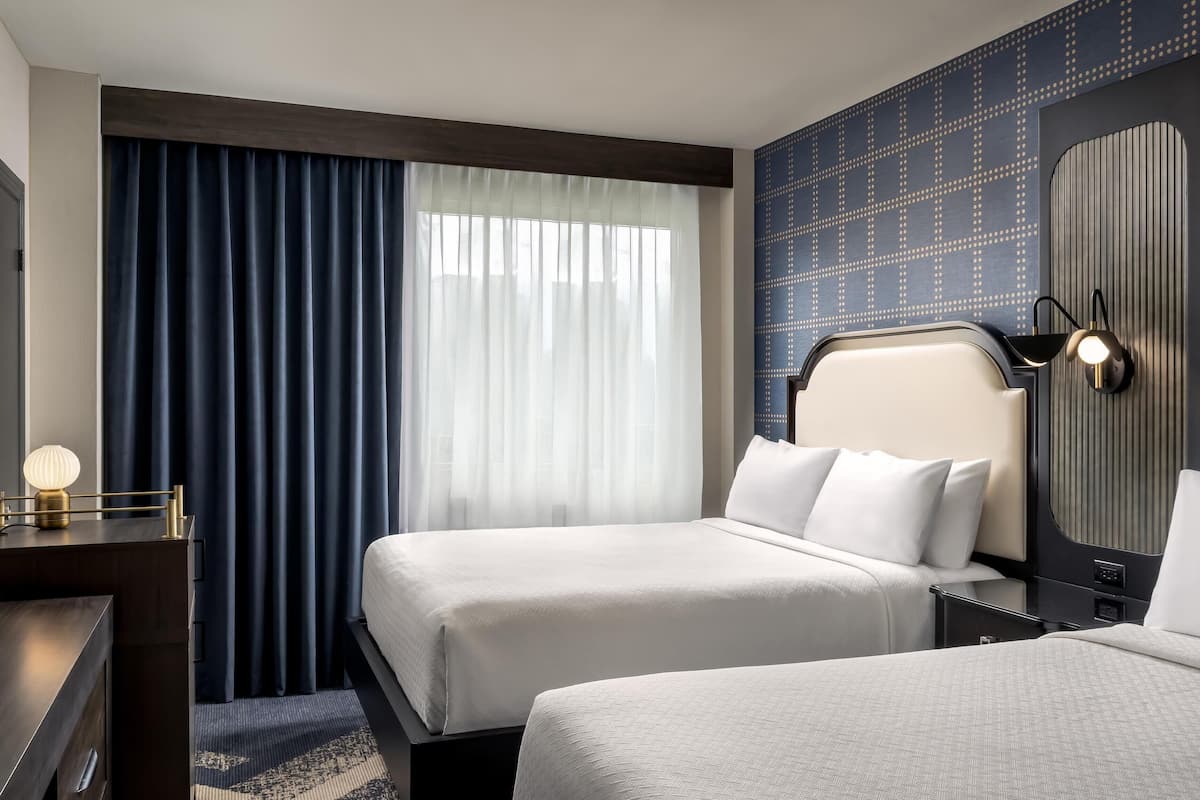 Una habitación de hotel con dos camas, un escritorio y una mesita de noche.