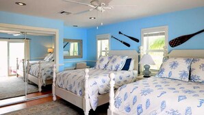 Camera da letto con due letti, una ventola a soffitto e un grande specchio.