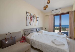 A hotel room with two beds, a sofa, a large window with a view, and artwork on the wall. - Marilia - Four Bedroom Villa, Sleeps 8 (Maleme)