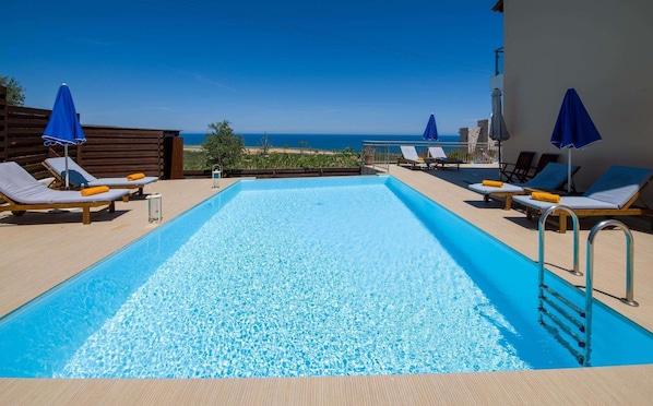 Relax by the ocean-view pool surrounded by comfortable loungers and shaded by umbrellas.