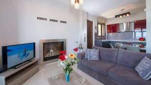 Een moderne woonkamer met een flatscreen televisie, een open haard en een bank met decoratieve kussens.