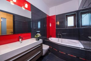 Features a bathtub, large mirror, and white sink.