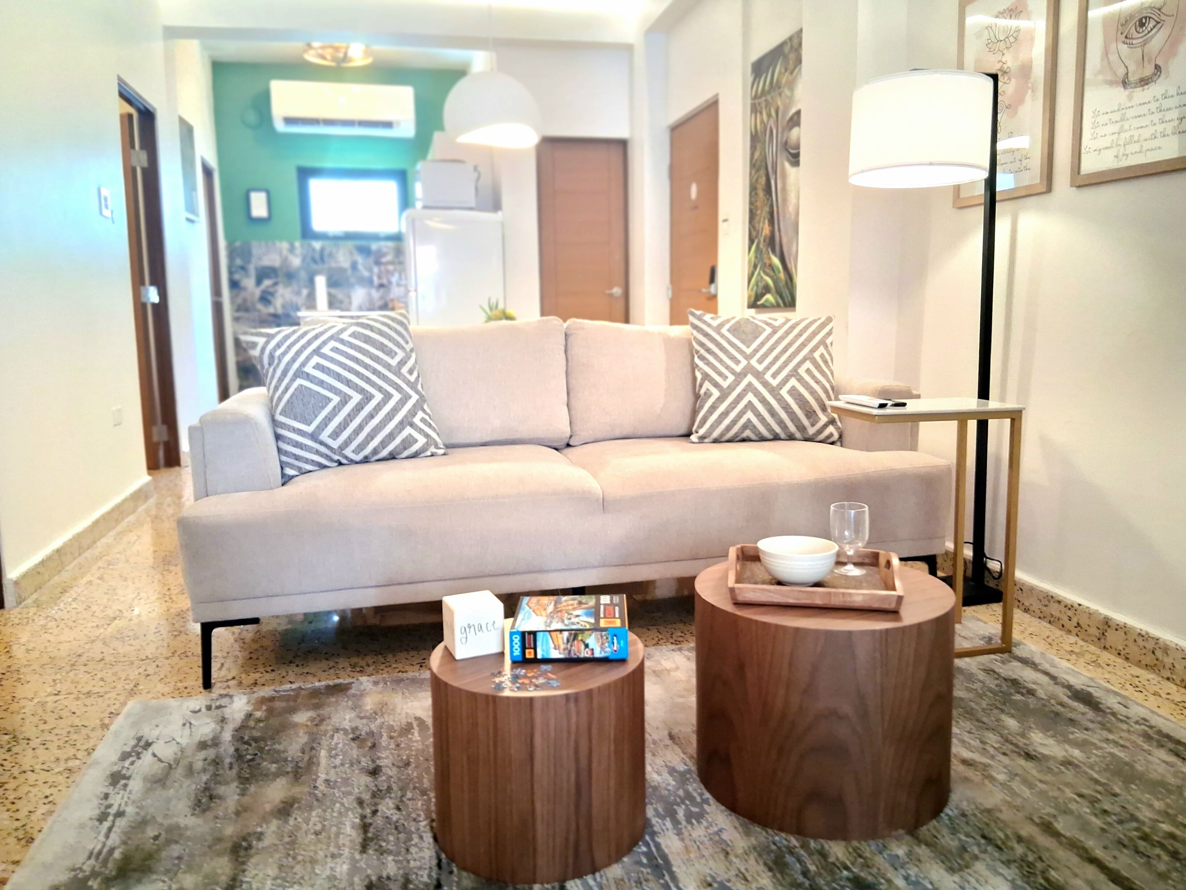 Un soggiorno moderno con un divano beige, due tavolini in legno e un tavolino da caffè.