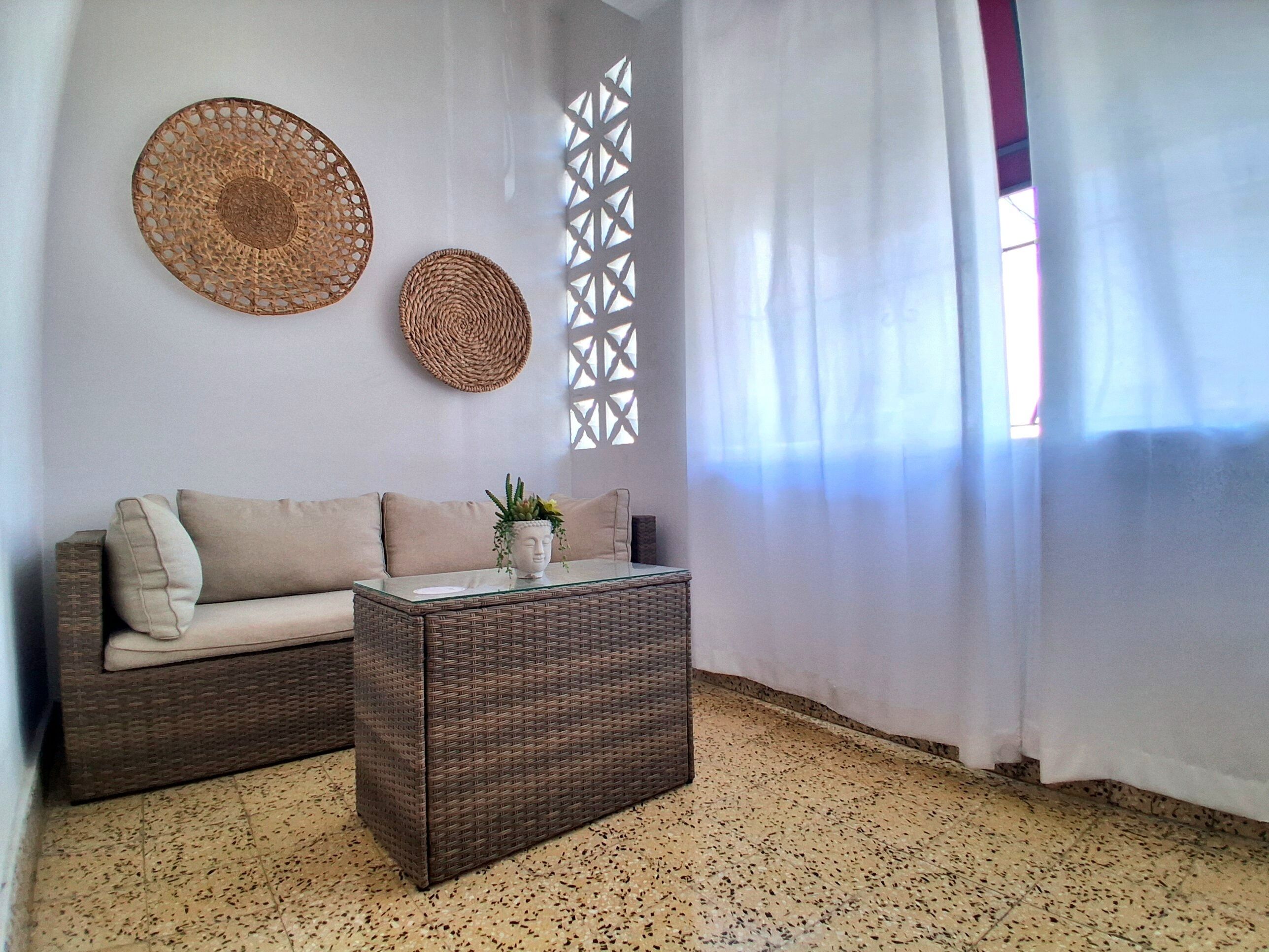 A living room with a sofa, a coffee table, and decorative wall hangings.