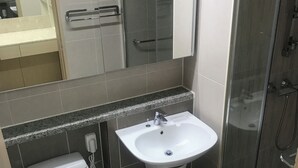 A bathroom with a toilet, sink, and shower.