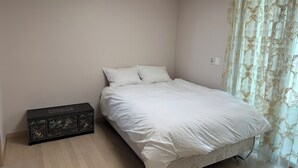 A bedroom with a bed, a nightstand, and a decorative chest of drawers.