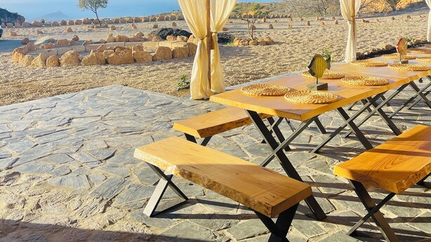 An outdoor dining area with stone flooring, wooden tables, and thatched umbrellas. - Las Cuevas - 3 bed finca in a serene setting (CN)