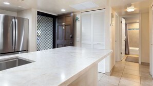 Una cocina moderna con encimera de mármol, electrodomésticos de acero inoxidable y vestidor.