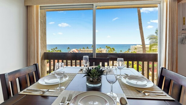 Mesa de comedor para dos con vista al océano y palmeras.