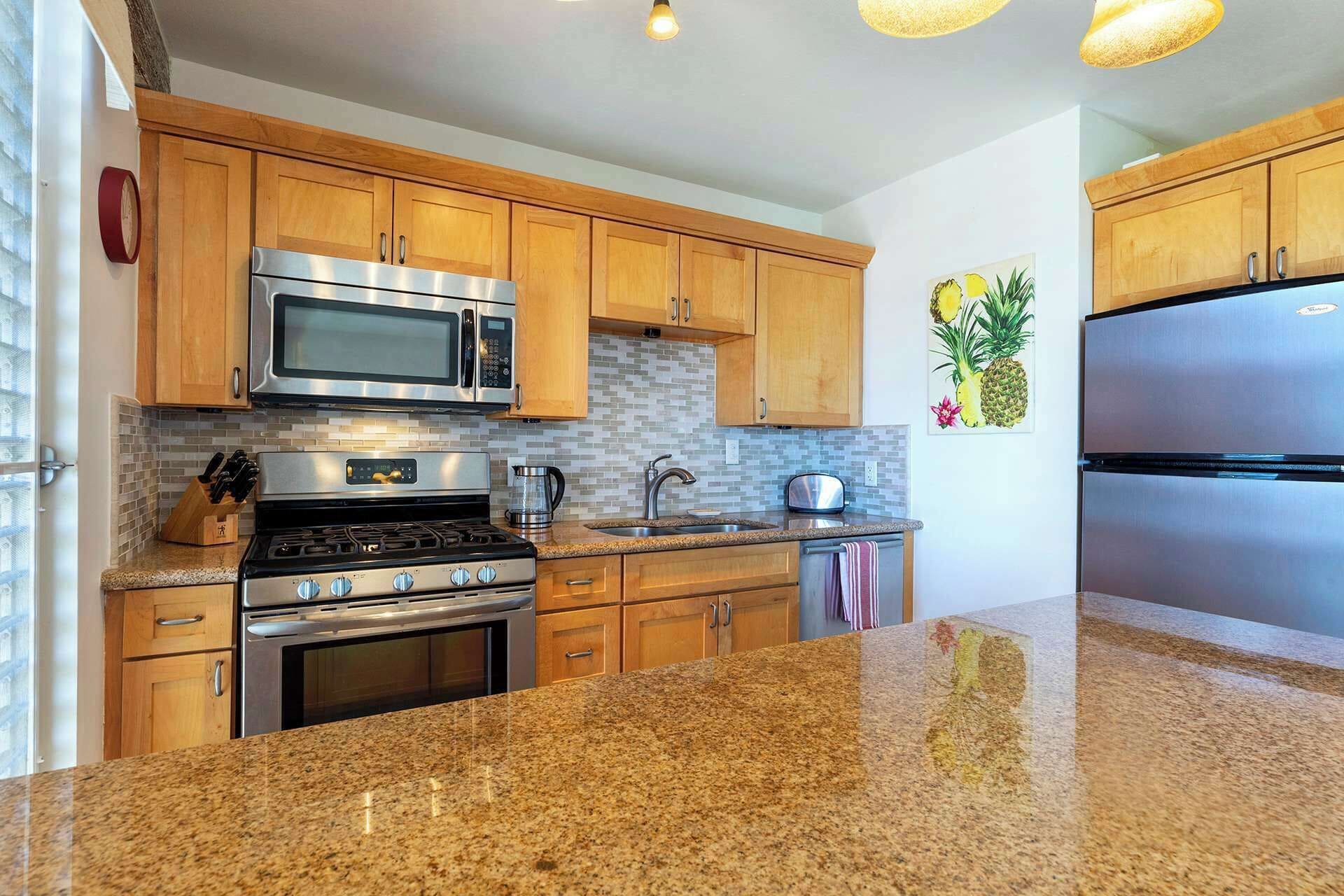 A modern kitchen with wooden cabinets, stainless steel appliances, granite countertops, and a tiled backsplash.