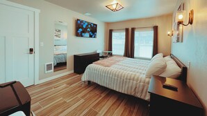 A bedroom with a bed, a dresser, a nightstand, a TV, and a window with curtains. - Walk to food & drinks, near lakes (Mossyrock)