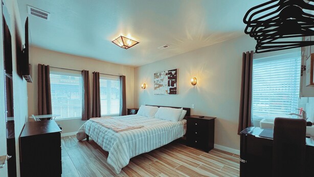 A modern bedroom with a large bed, bedside tables, a desk, and a hanging light fixture. - Walk to food & drinks, near lakes (Mossyrock)