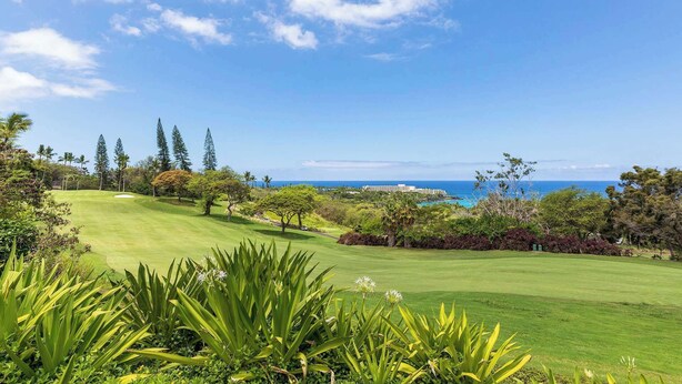 Un parcours de golf avec vue sur l’océan et un hôtel en arrière-plan.
