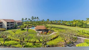 Un resort con piscina, una construcción de techo de paja y un campo de golf.
